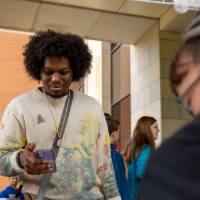 Student holds cell phone while looking at display during Student Small Business Market.